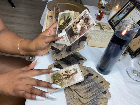 Mikayla Rose, Black woman spiritual philosopher and astrologer, at her altar with tarot cards, candles, the bible, and ancestral offerings.